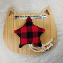 Load image into Gallery viewer, Red and black plaid cat toy shaped like a star, with a metal ruler placed above it, laying on a wooden board shaped like a cat on a white fuzzy mat with the leaves of a plant in the edge of the photo.