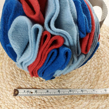 Load image into Gallery viewer, Close up photo of a blue and red snuffle ball toy made out of fleece next to a measuring tape on a light coloured background.
