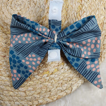 Load image into Gallery viewer, Abstract Teal with Pink Collar Bow. Help your pup put their best paw forward by wearing one of these pretty bows on their collar. Worn to the side, up front or at the back, its versatility makes dressing up an everyday possibility! This collar bow is suitable as a cat collar and a dog collar. Measures 5.5” at its widest point. Made from 100% cotton fabric in a variety of patterns. Fastens to collars up to 1” wide. Elastic and snap fastener. Wiggles and Whiskers Canada Pet Accessories.