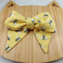 Load image into Gallery viewer, Collar Bow - Bees! Pet collar can be worn as a cat collar or dog collar. Help your pup put their best paw forward by wearing one of these pretty bows on their collar. Worn to the side, up front or at the back, its versatility makes dressing up an everyday possibility! Measures 5.5” at its widest point. Made from 100% cotton fabric in a variety of patterns. Fastens to collars up to 1” wide. Elastic and snap fastener. Wiggles and Whiskers Canada Pet Accessories.
