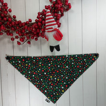 Load image into Gallery viewer, Dog Bandana made out of green fabric with festive polka dots on it laying flat on a white background with a stuffed toy dog leaning against an artificial red wreath.
