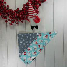 Load image into Gallery viewer, Dog Bandana made out of fabric with polar bears on a light blue background on one side and snowflakes on a silver background on the other, laying flat on a white background with a toy gnome leaning against an artificial red wreath.
