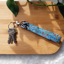 Load image into Gallery viewer, Carry your keys in style with these wrist lanyards made in various pet themed fabrics. &#39;Dog Words&#39; Version - Measures 5.5&quot; long x 1&quot; wide. Happy Dogs&#39; Version - Measures 6&quot; long x 1&quot; wide. Reinforced with twill tape, double stitching and interfacing for stiffness. Stainless steel D-ring measures ¾&quot; in diameter with an attached swiveling lobster clasp. 1” Stainless steel key ring included. Wiggles and Whiskers Canada Pet Accessories.
