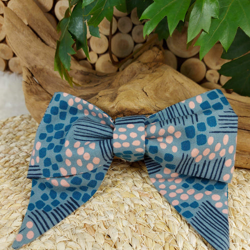 Abstract Teal with Pink Collar Bow. Help your pup put their best paw forward by wearing one of these pretty bows on their collar. Worn to the side, up front or at the back, its versatility makes dressing up an everyday possibility! This collar bow is suitable as a cat collar and a dog collar.  Measures 5.5” at its widest point. Made from 100% cotton fabric in a variety of patterns. Fastens to collars up to 1” wide. Elastic and snap fastener. Wiggles and Whiskers Canada Pet Accessories.