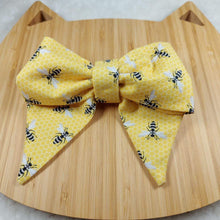Load image into Gallery viewer, Collar Bow - Bees! Pet collar can be worn as a cat collar or dog collar. Help your pup put their best paw forward by wearing one of these pretty bows on their collar. Worn to the side, up front or at the back, its versatility makes dressing up an everyday possibility! Measures 5.5” at its widest point. Made from 100% cotton fabric in a variety of patterns. Fastens to collars up to 1” wide. Elastic and snap fastener. Wiggles and Whiskers Canada Pet Accessories.
