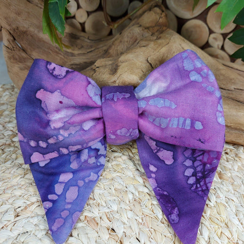 Purple perfection bow collar. Help your pup put their best paw forward by wearing one of these pretty bows on their collar. Worn to the side, up front or at the back, its versatility makes dressing up an everyday possibility! This collar bow is suitable as a cat collar and a dog collar.  Measures 5.5” at its widest point. Made from 100% cotton fabric in a variety of patterns. Fastens to collars up to 1” wide. Elastic and snap fastener. Wiggles and Whiskers Canada Pet Accessories.