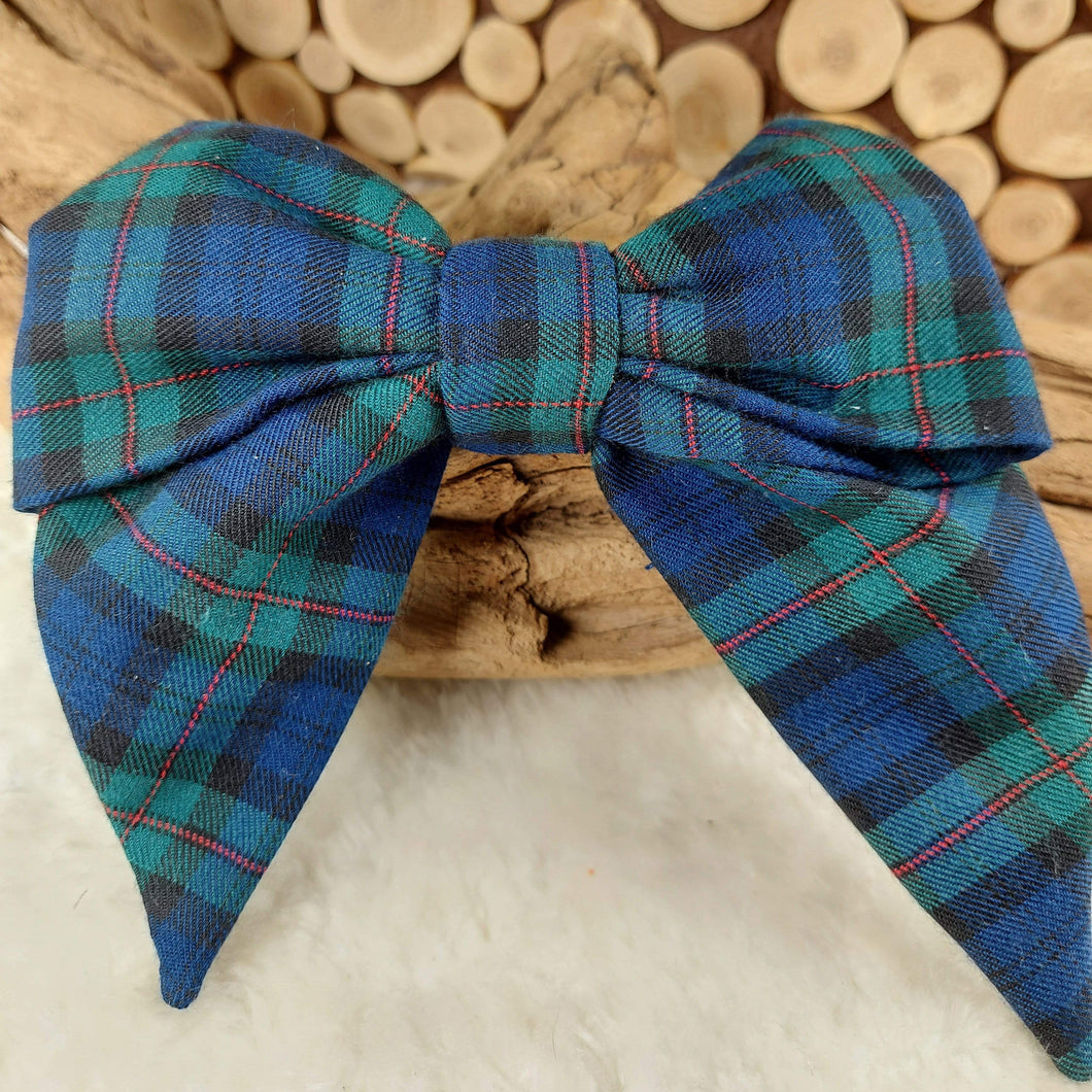 Plaid Collar Bow. Help your pup put their best paw forward by wearing one of these pretty bows on their collar. Worn to the side, up front or at the back, its versatility makes dressing up an everyday possibility! This collar bow is suitable as a cat collar and a dog collar.  Measures 5.5” at its widest point. Made from 100% cotton fabric in a variety of patterns. Fastens to collars up to 1” wide. Elastic and snap fastener. Wiggles and Whiskers Canada Pet Accessories.